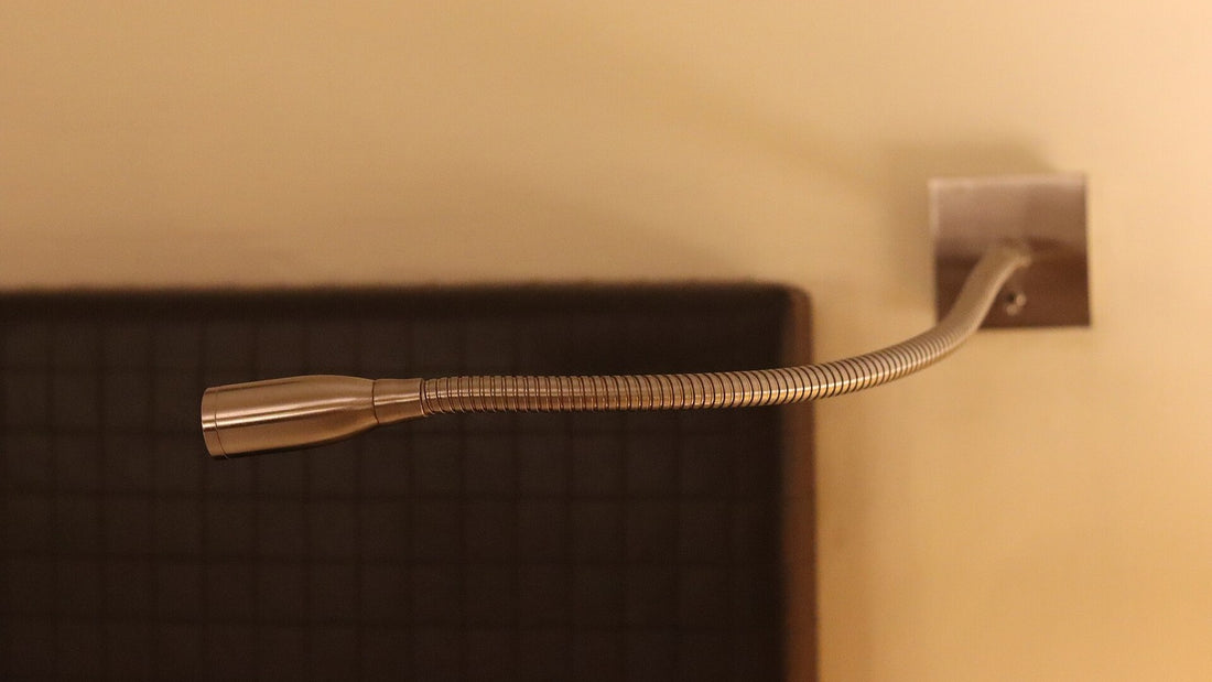 A warm bedside lamp glowing softly against a dark headboard in the evening