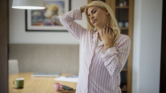 Woman gently stretching her neck and shoulders in a sunlit home kitchen
