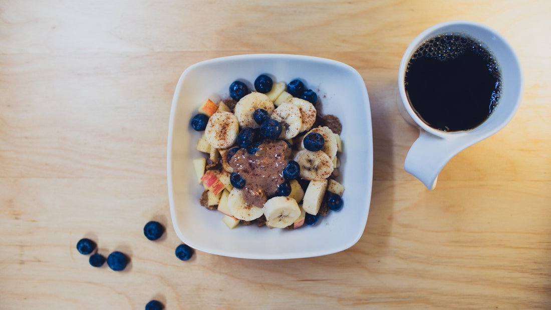 A bowl of fruit and breakfast ingredients on a table.
