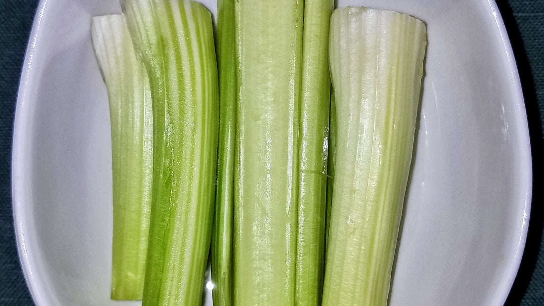 Freshly cut crisp celery sticks resting in a white serving dish