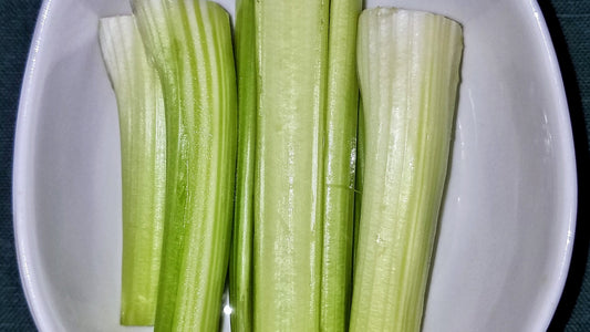 Freshly cut crisp celery sticks resting in a white serving dish