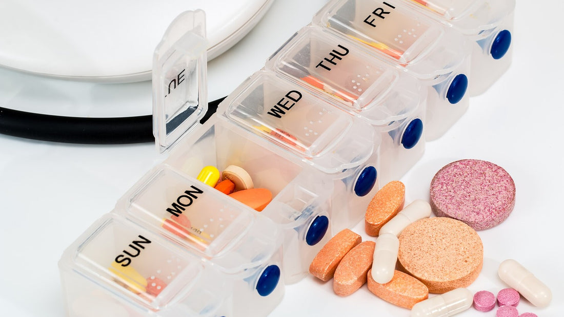 Weekly supplement organizer with assorted capsules on a white surface