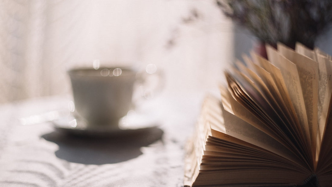 Open book beside a cup of tea on a quiet table
