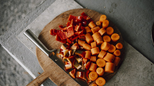 Fresh vegetables being chopped on a wooden cutting board in a kitchen