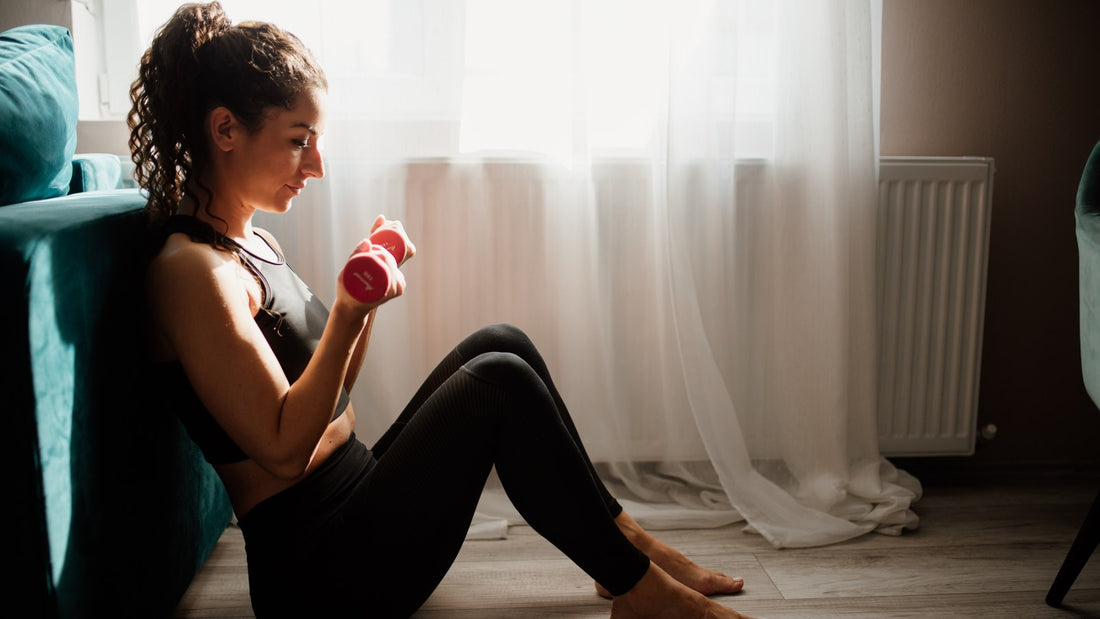 A woman exercising with a dumbbell in a bright living room