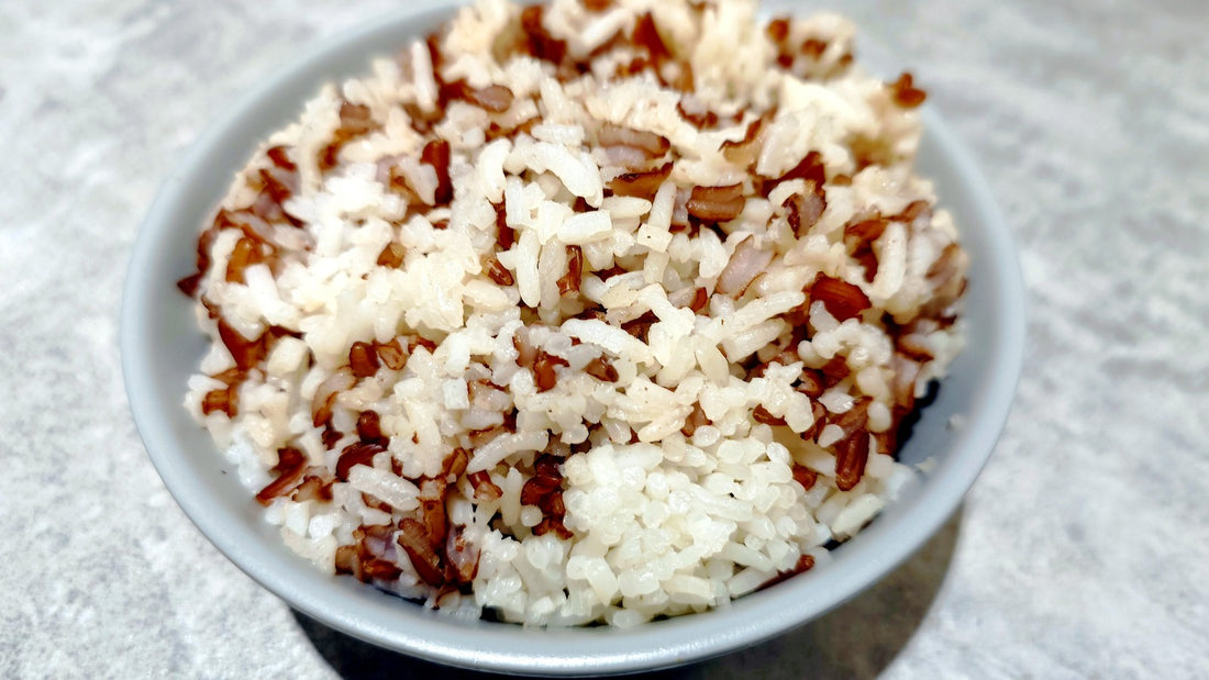Bowl of cooked white and brown rice on a light surface