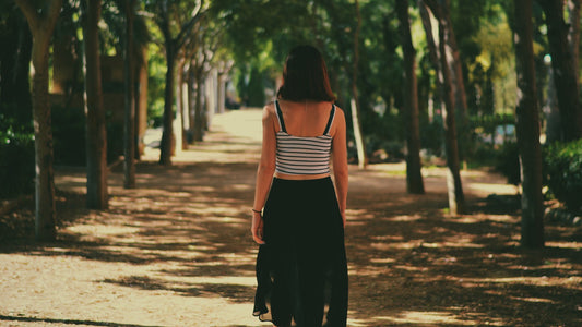 Woman walking along a shaded tree-lined path