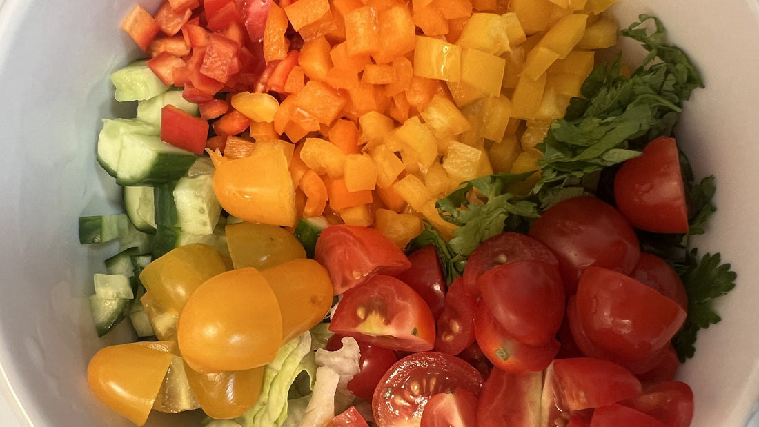 A bowl filled with colorful freshly chopped tomatoes, peppers, and cucumbers ready for a salad