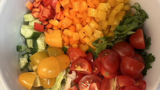 A bowl filled with colorful freshly chopped tomatoes, peppers, and cucumbers ready for a salad