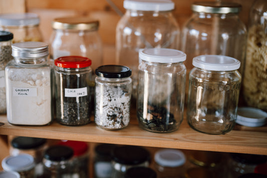 Clear glass pantry jars arranged on a wooden shelf