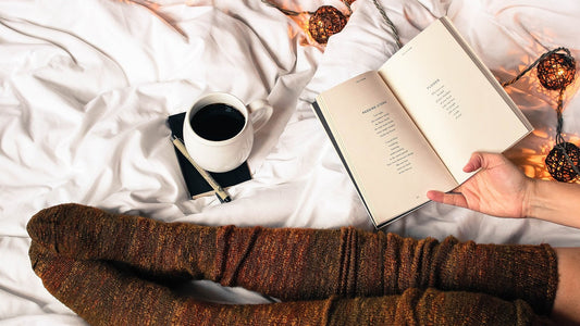 Person reading an open book beside a warm drink and soft evening lights