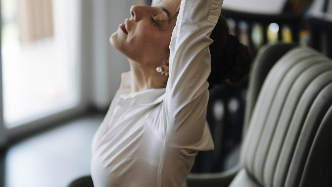 Woman stretching her arms while seated in a bright room