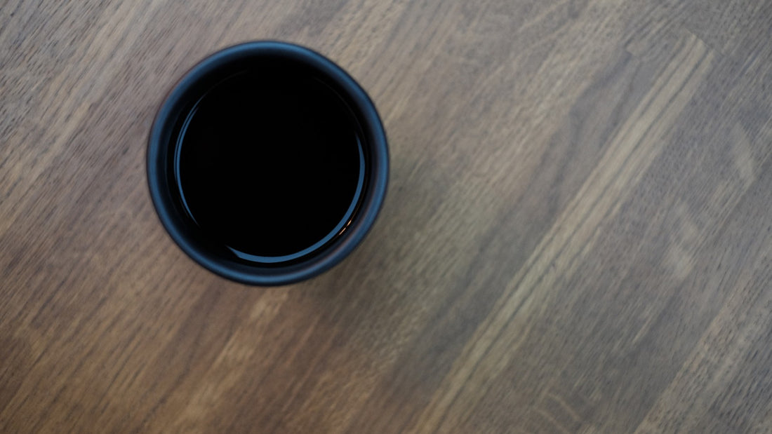A plain black cup of coffee on a wooden table