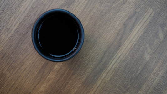 A plain black cup of coffee on a wooden table