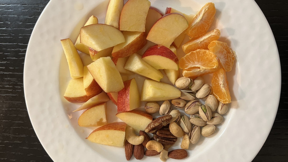 Plate of apple slices, citrus, and mixed nuts for a simple afternoon snack routine