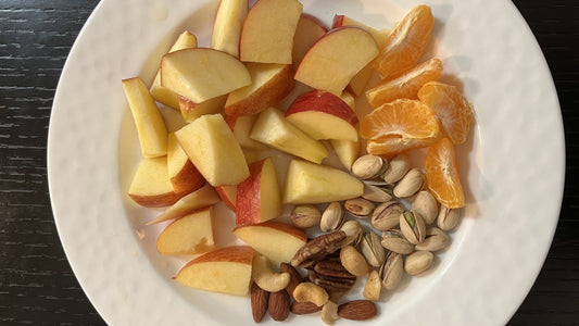 Plate of apple slices, citrus, and mixed nuts for a simple afternoon snack routine
