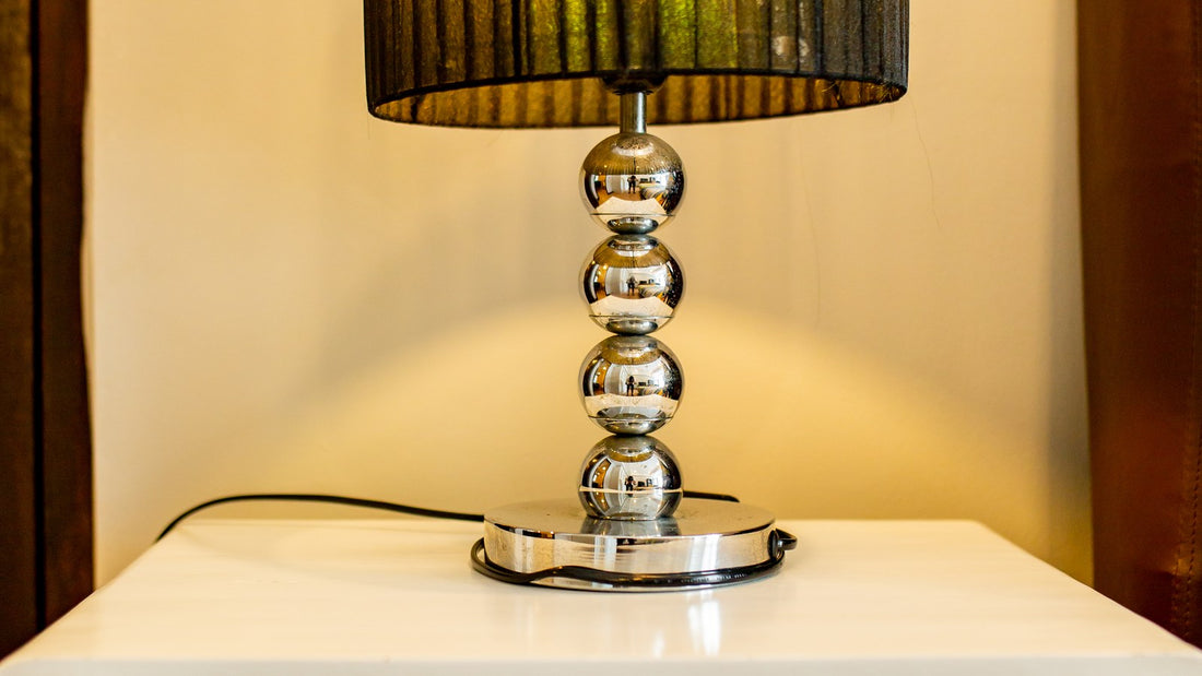 A decorative table lamp on a white nightstand in a bedroom, no phone or people visible
