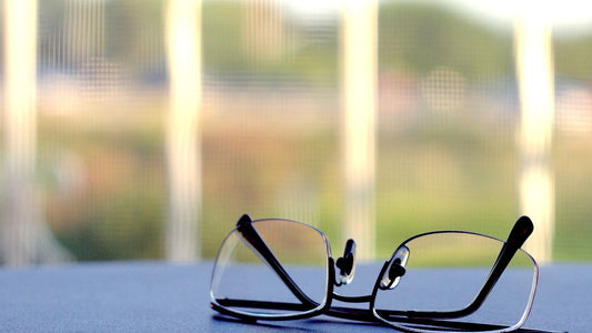 Reading glasses resting on a table near a bright window