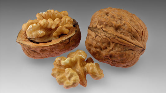 Shelled walnut halves and a whole walnut in shell on a clean surface