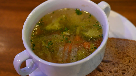 Steaming bowl of homemade vegetable broth garnished with fresh parsley