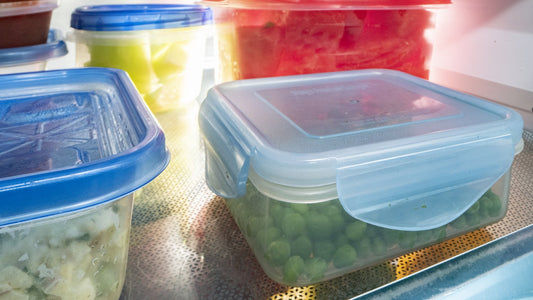 Clear food containers with prepared vegetables on a refrigerator shelf