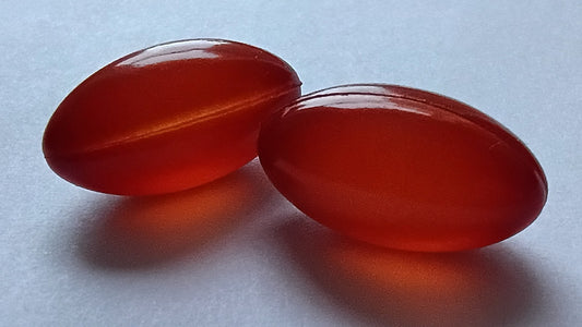 Plain amber supplement capsules arranged on a white surface