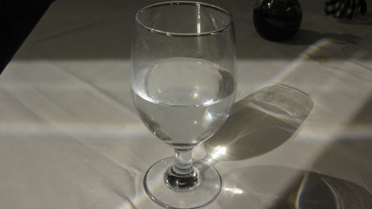 A clear glass of water on a simple surface with light passing through it