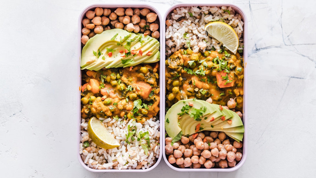 Two meal containers with rice, chickpeas, avocado, and vegetables