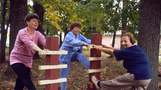 Three older women using outdoor rails for a standing stretch