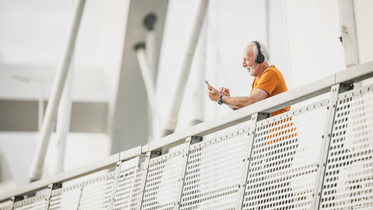 Older man wearing headphones and looking at music on his phone