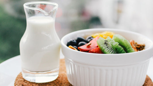 Breakfast bowl with fruit beside a small pitcher of milk