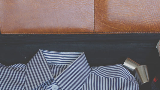 A plain close-up photo of a brown suitcase packed with a striped shirt