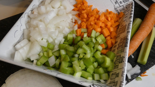 Diced onion, carrot, and celery arranged in a dish for simple meal preparation.