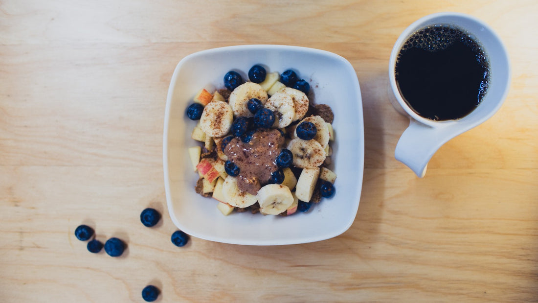A plain overhead photo of a breakfast bowl topped with banana and blueberries