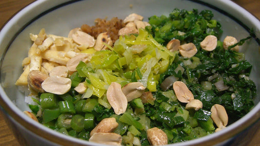 Bowl of rice, tofu, green vegetables, and peanuts on a wooden table