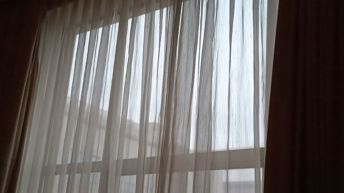 Soft morning light filtering through white curtains at a bedroom window