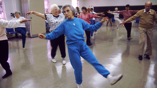 Older adults in a community room taking part in a group movement class
