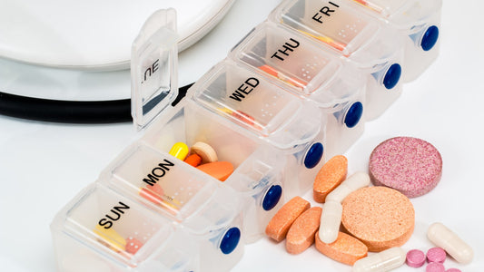 Weekly pill organizer with assorted capsules and tablets on a white table