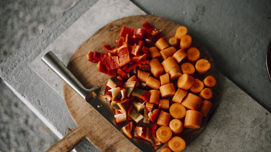 Chopped carrots and red peppers on a wooden cutting board