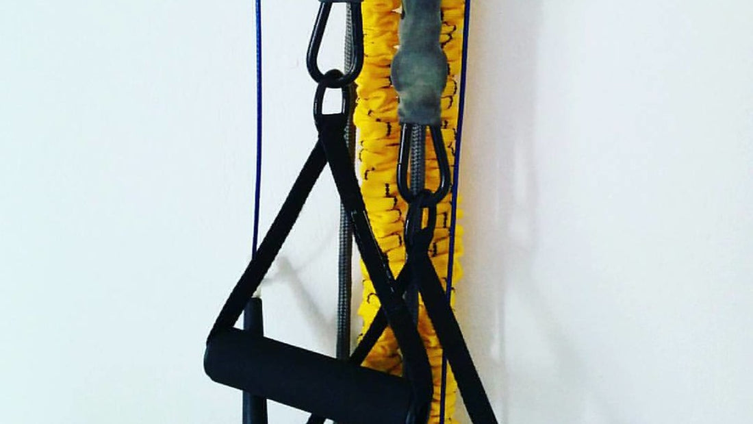 Yellow resistance tubes and black exercise handles hanging against a white wall