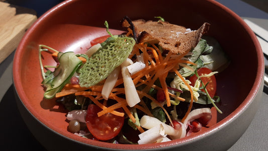 Bowls of leafy salad with tomatoes, cucumber, radishes and mushrooms on an outdoor table