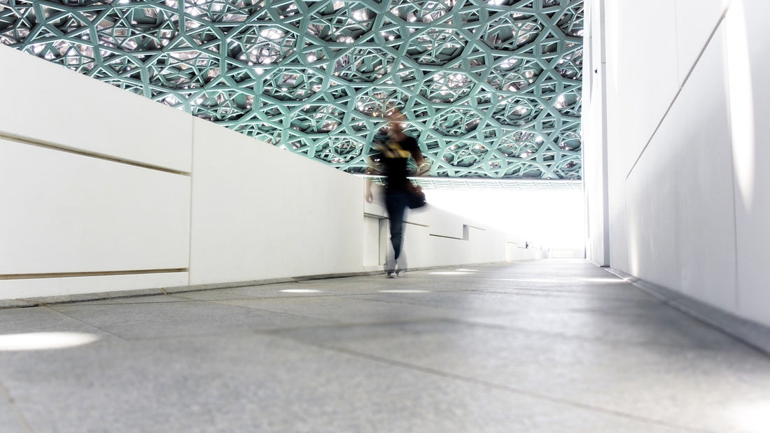 Person walking through a modern indoor corridor beneath a geometric ceiling