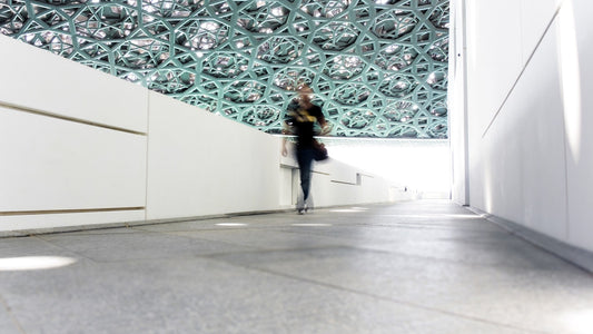 Person walking through a modern indoor corridor beneath a geometric ceiling