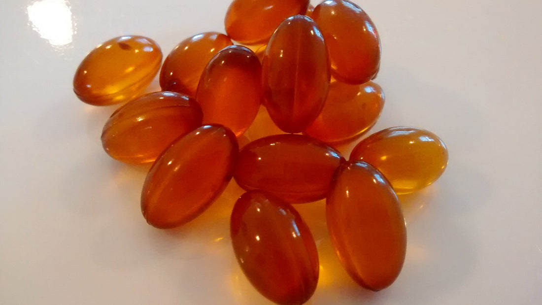Unbranded amber supplement softgels on a plain white surface