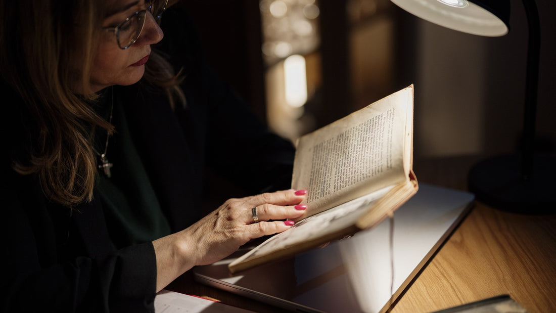Woman reading a book under a focused lamp in a quiet room