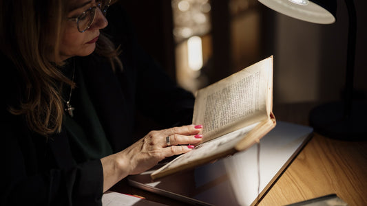 Woman reading a book under a focused lamp in a quiet room
