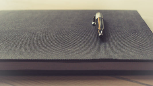 Black pen resting on a closed gray notebook