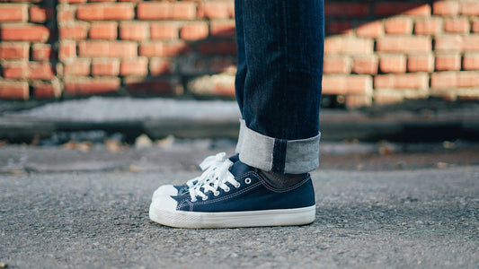 Person wearing laced navy walking shoes beside a brick wall