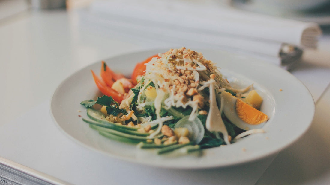 A colorful salad with greens, cucumber, tomato, egg, and a crunchy topping