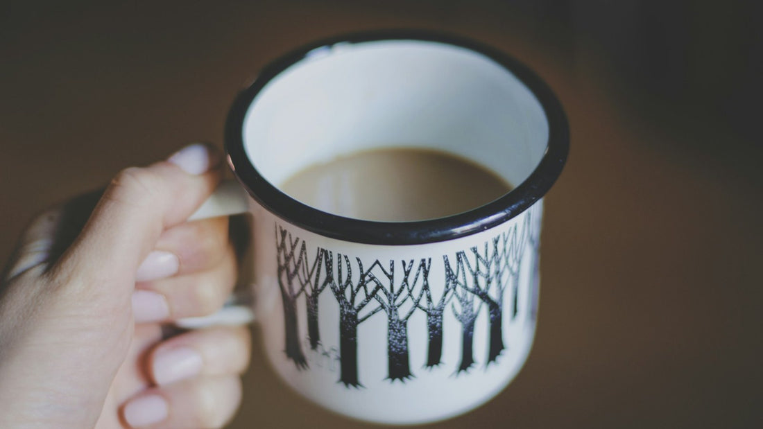 Hand holding a warm drink in a patterned white mug during a quiet evening routine